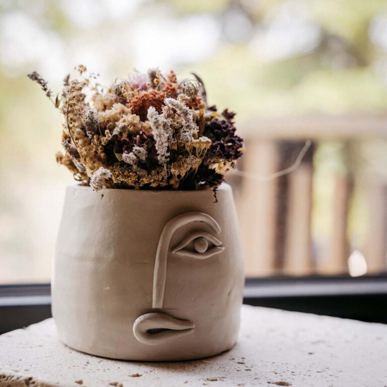 Blumentopf mit Gesicht und Trockenblume