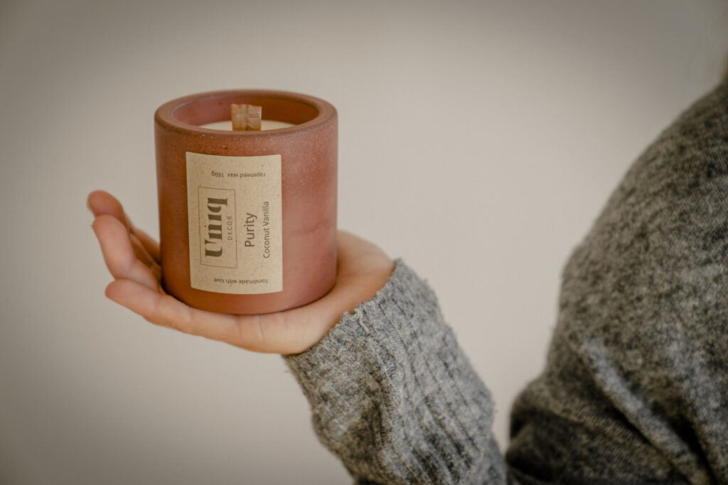 rostbraune betongefäß mit rapswachskerze und holzdocht